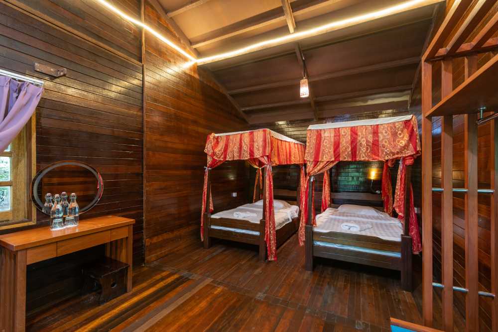 Chalet room with two canopy beds and red drapes
